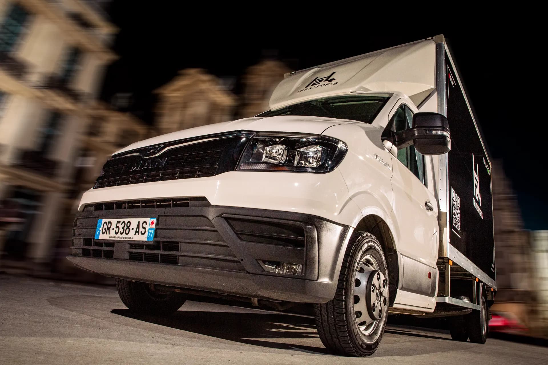 Camion H24 Transports de nuit devant des immeubles parisiens