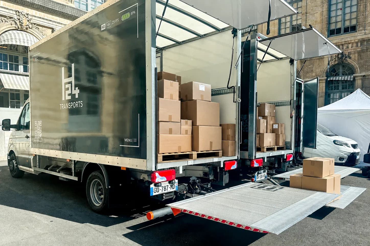 Camion H24 Transports hayon déployé, chargé de cartons sur palettes