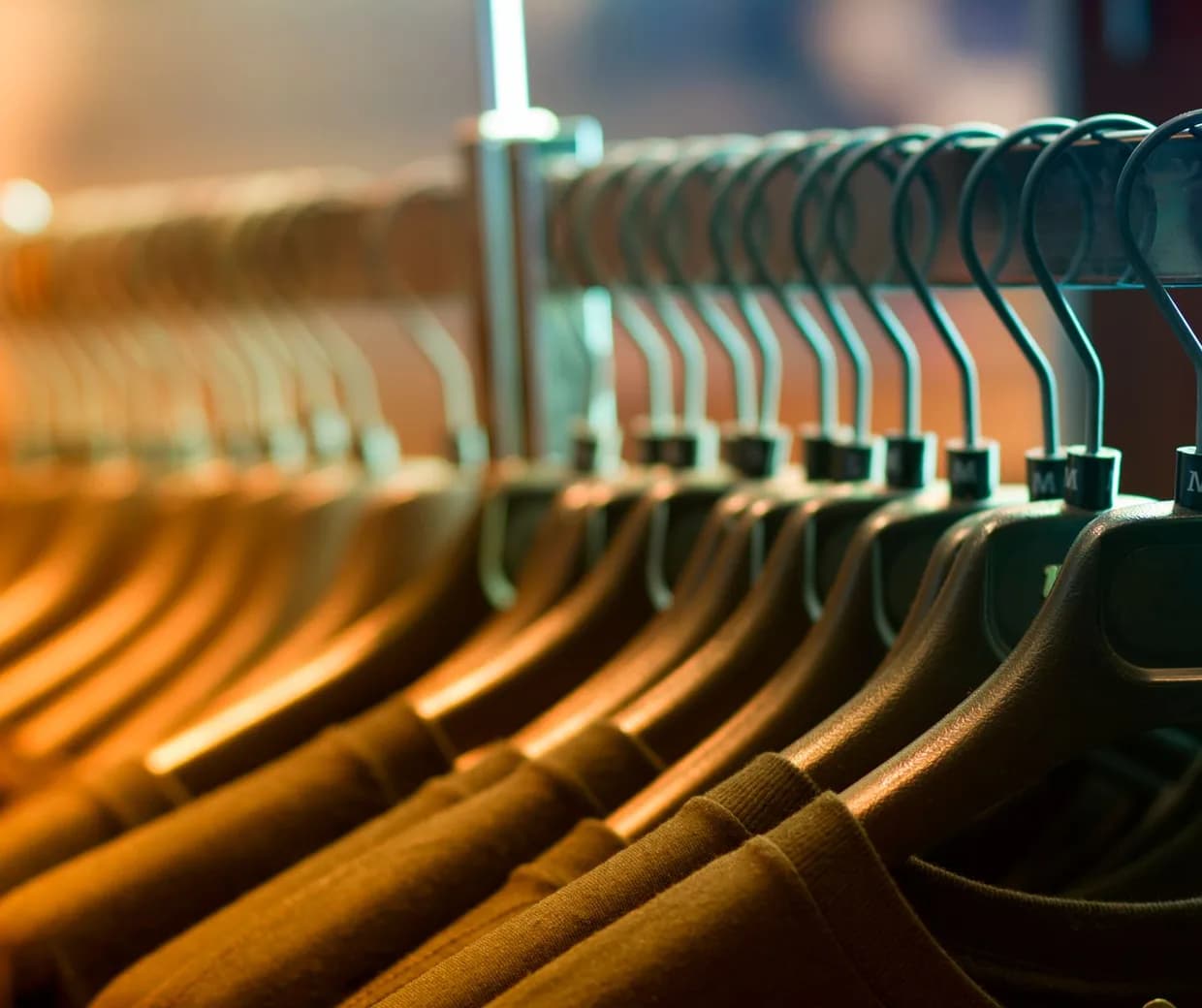 Rangée serrée de vêtements sur cintres le long d'une barre de penderie