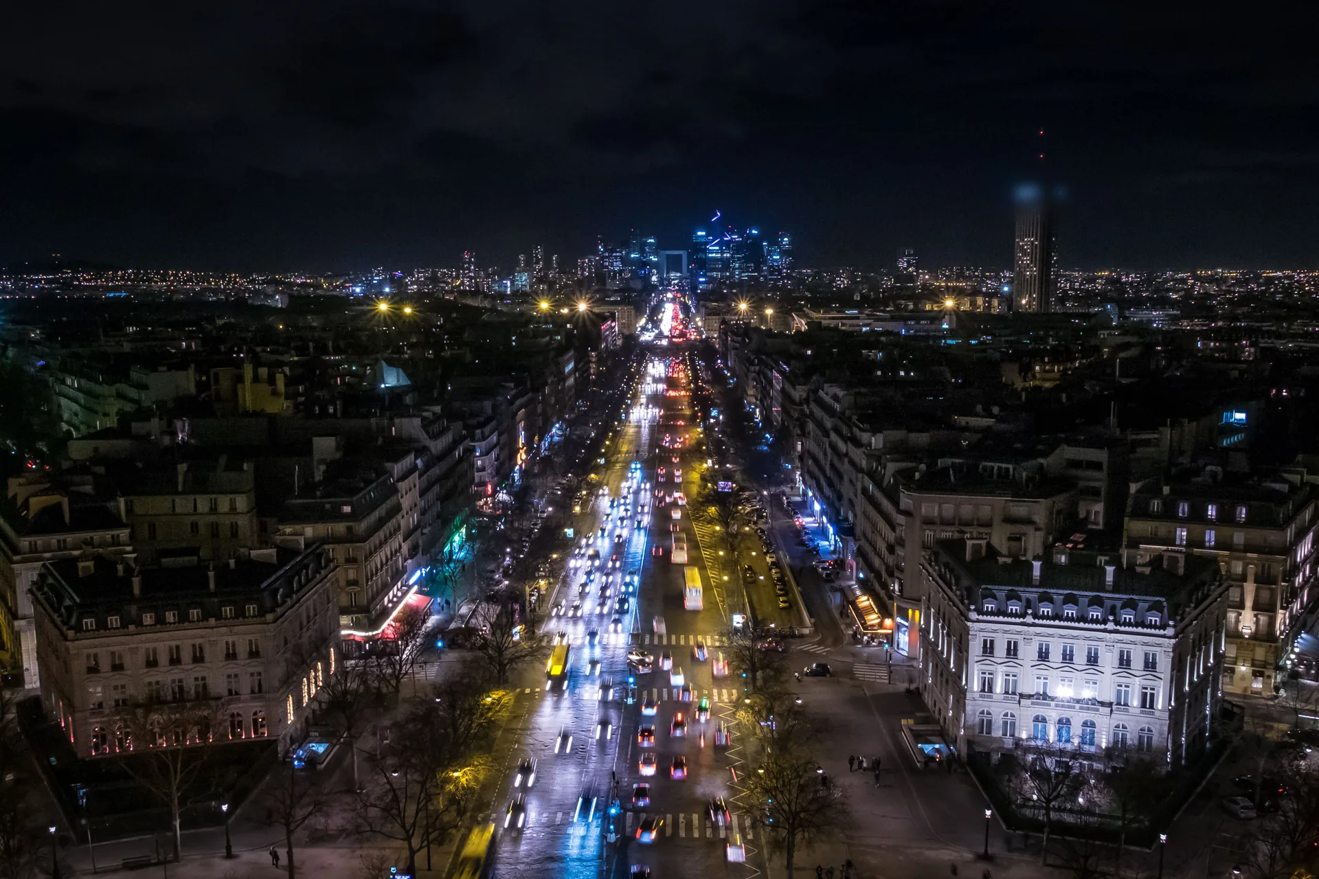 Paris la nuit vu depuis l'Arc de Triomphe, avenue de la Grande-Armée éclairée et tours de La Défense à l'horizon